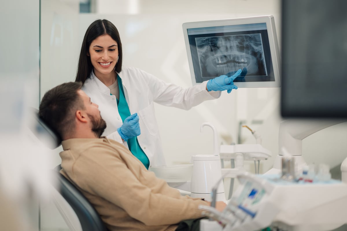 Dentista mostrando radiografía a paciente en clínica moderna